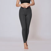 Woman wearing a black sports bra and gray active tights on a white background