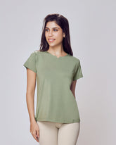 Woman wearing a green Cosy Cotton T-Shirt and beige leggings on a white background