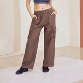 Woman in a blue top and brown cargo pants standing in a modern architectural setting.