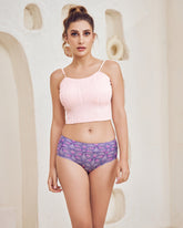 Woman wearing a pink top and purple patterned underwear against a neutral background