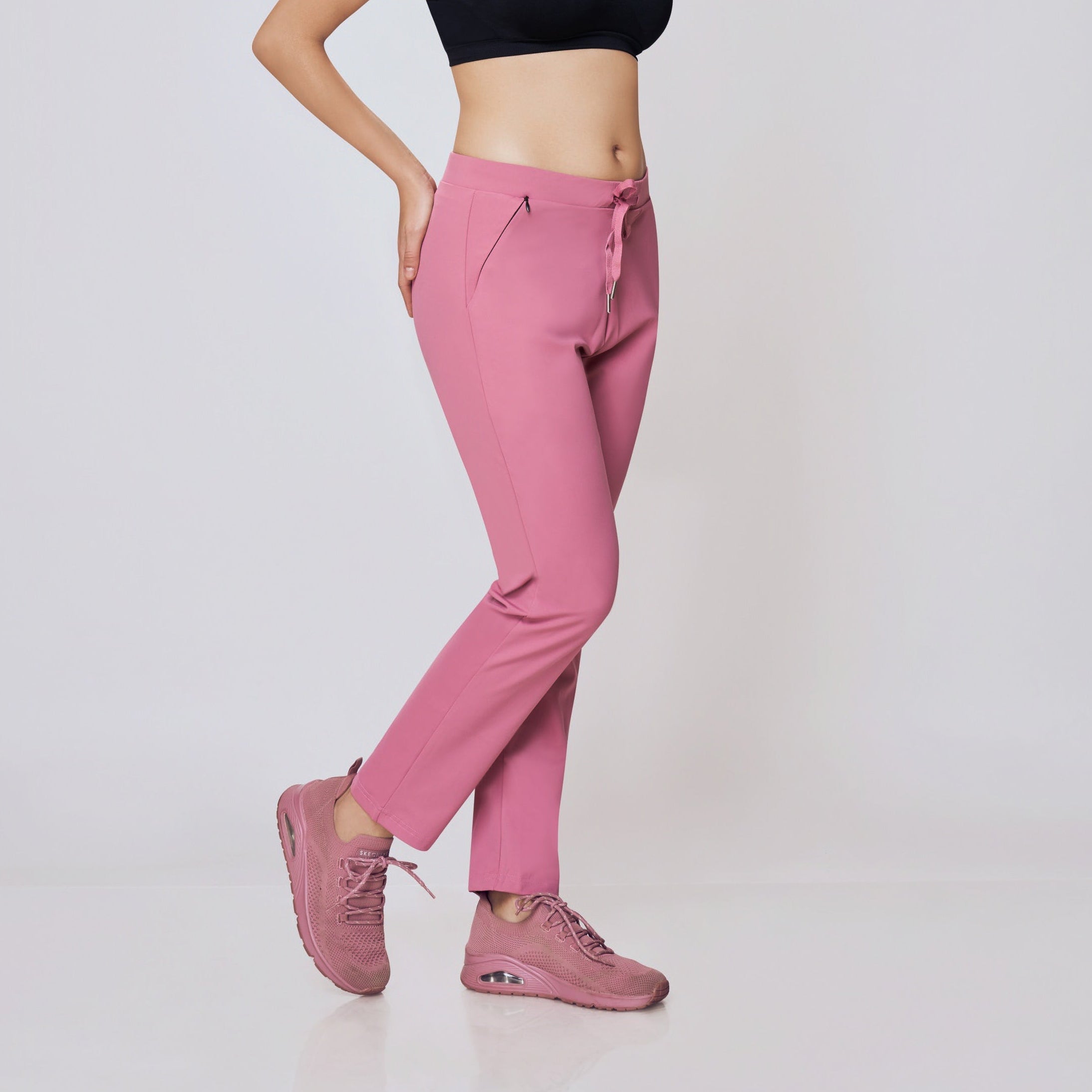 Woman wearing a black sports bra and pink pants on a white background