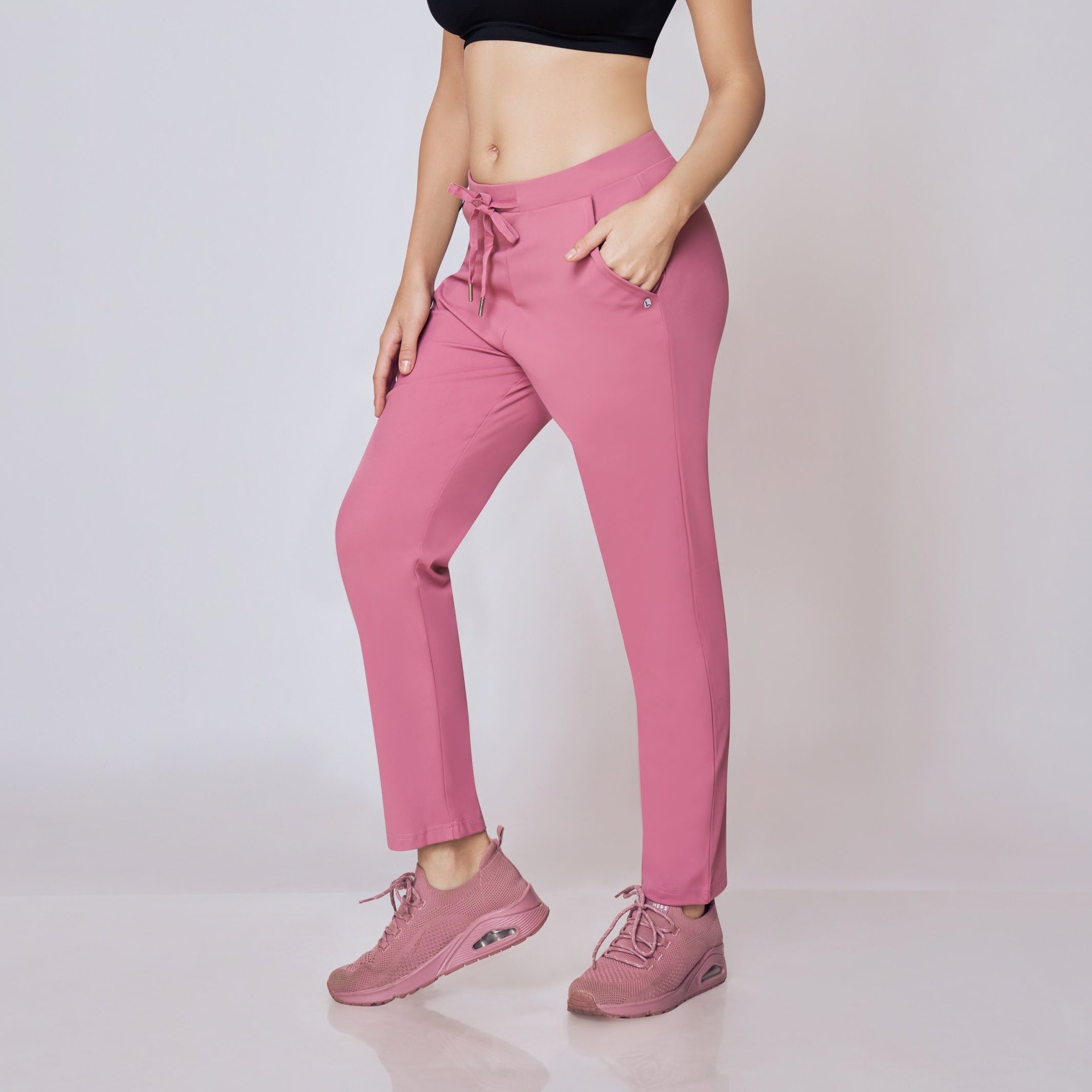 Woman wearing a black sports bra and pink pants on a white background