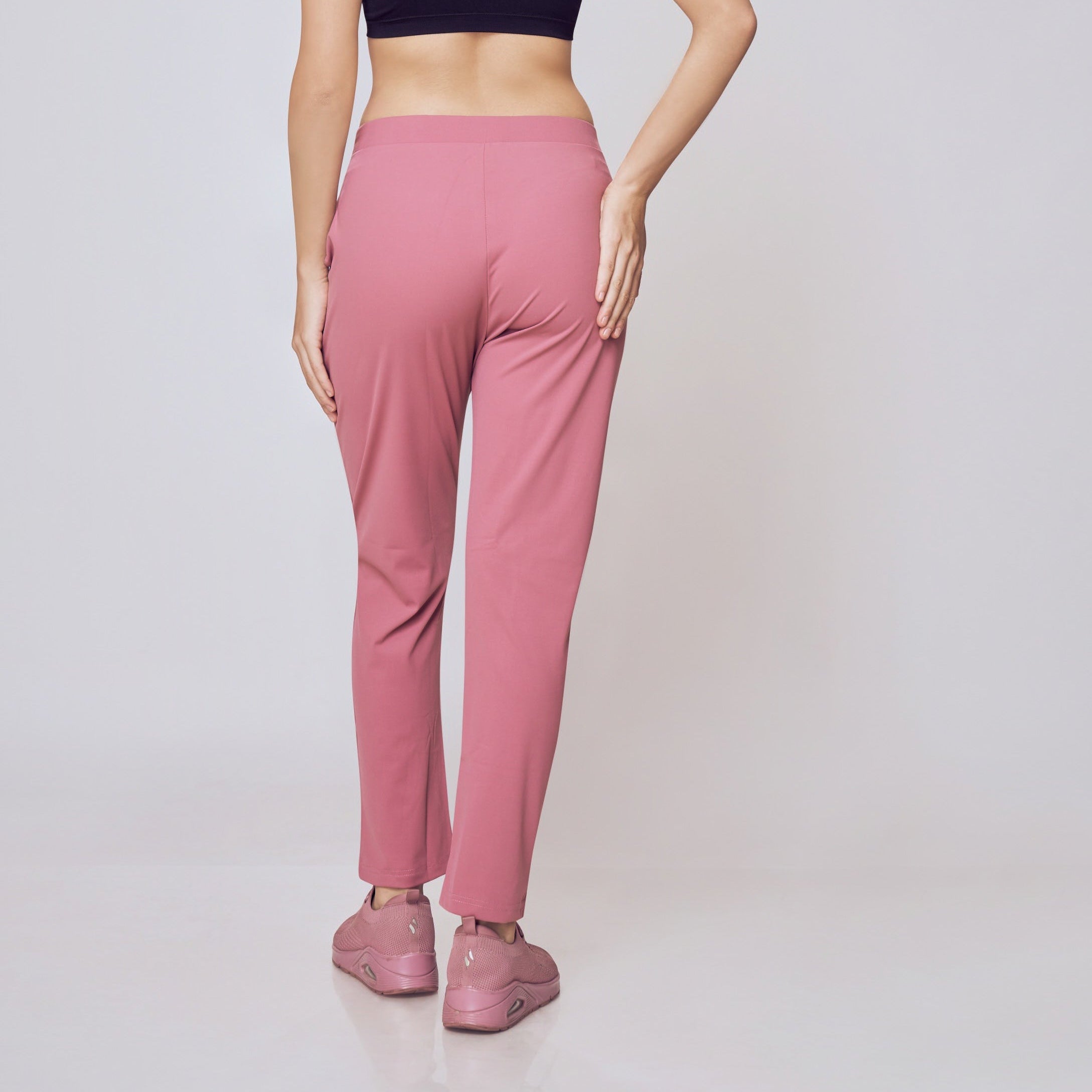 Woman wearing a black sports bra and pink leggings on a white background