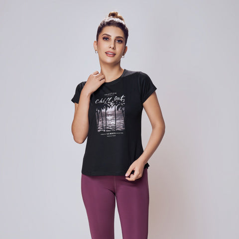 Woman wearing a black t-shirt with a graphic design and purple leggings on a white background