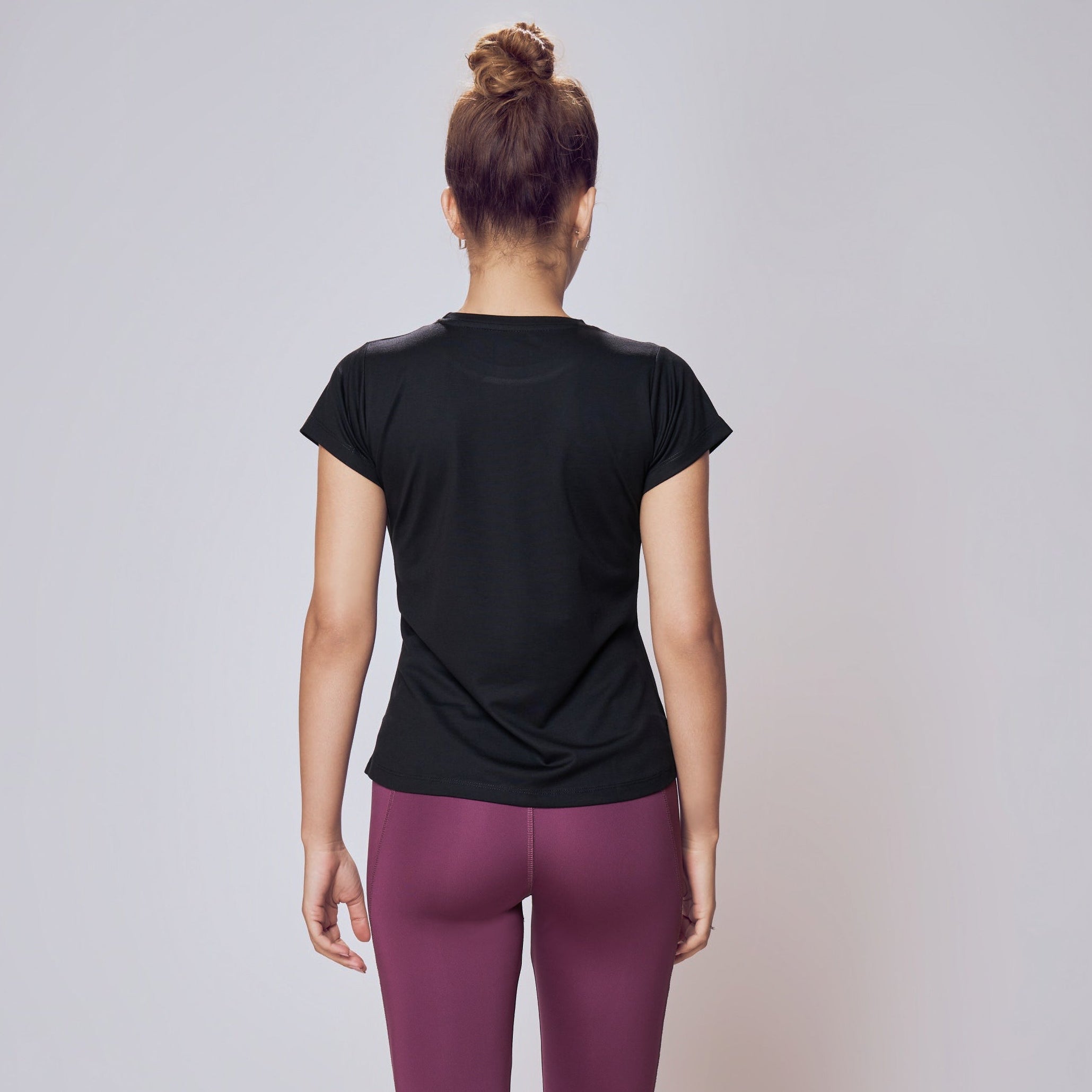 Person wearing a black t-shirt and purple leggings on a plain background