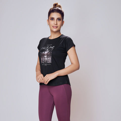 Woman wearing a black t-shirt and purple leggings on a white background