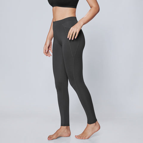 Woman wearing a black sports bra and dark gray Classic Dry Fit High-Rise Active Tights on a light gray background