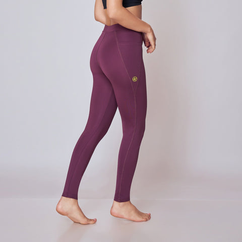 Woman wearing a black top and wine leggings on a white background