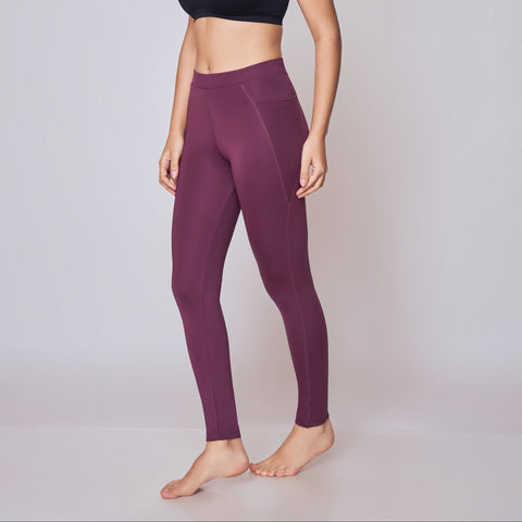 Woman wearing a black sports bra and Wine leggings on a white background
