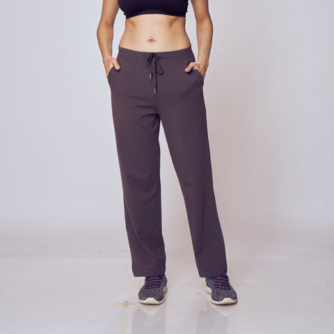 Woman wearing a black sports bra and dark gray Classic Flex Regular Fit Track Pants on a white background