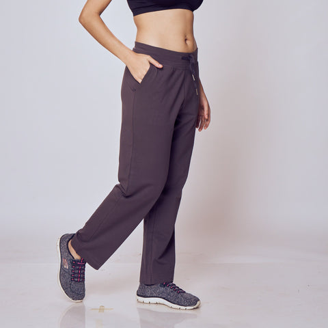 Woman wearing a black sports bra and dark gray Classic Flex Regular Fit Track Pants on a white background