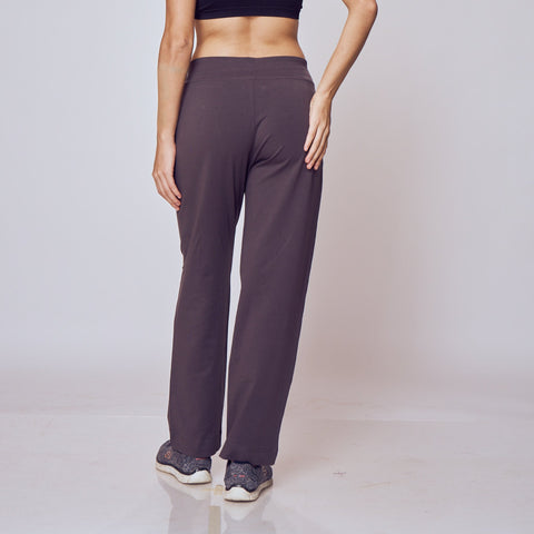 Woman wearing a black sports bra and dark gray Classic Flex Regular Fit Track Pants on a white background