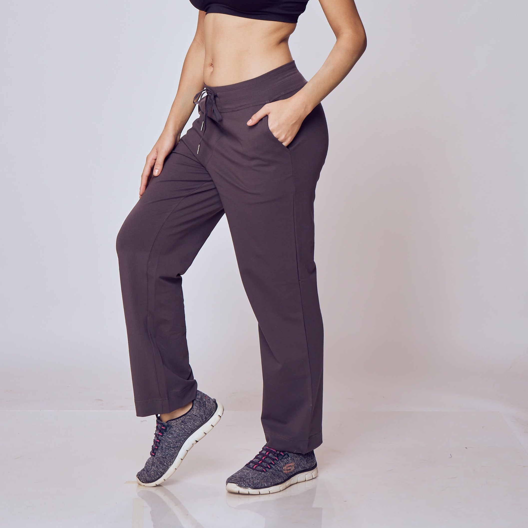 Woman wearing a black sports bra and dark Classic Flex Regular Fit Track Pants on a white background