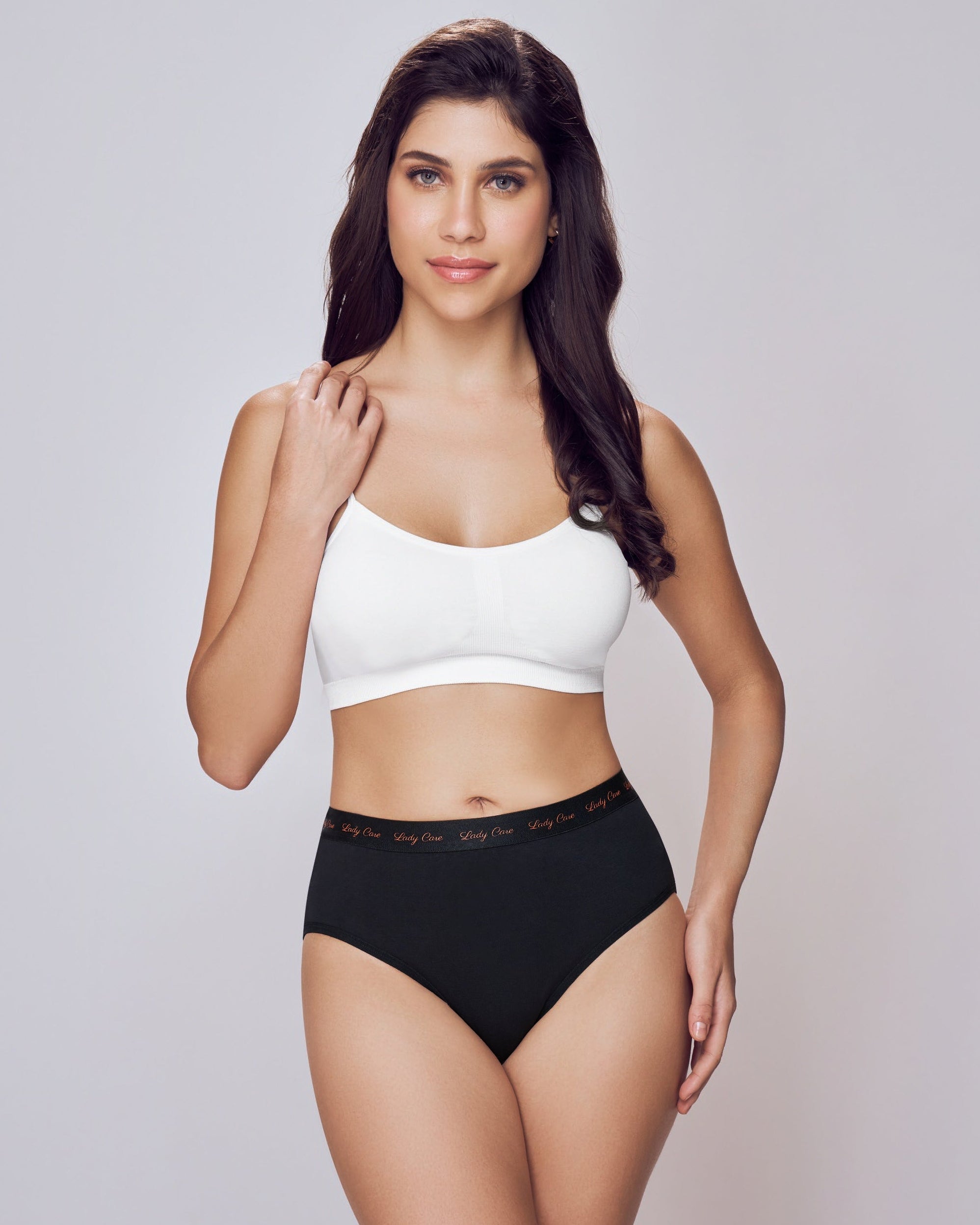 Woman wearing a white sports bra and black high-waisted shorts on a plain background