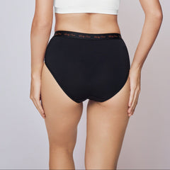 Woman wearing a white bikini top and black high-waisted bottoms on a plain background