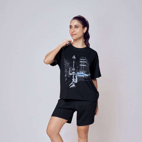 Woman wearing a black t-shirt and shorts with graphic designs on a plain background. Co-ord Set for Women