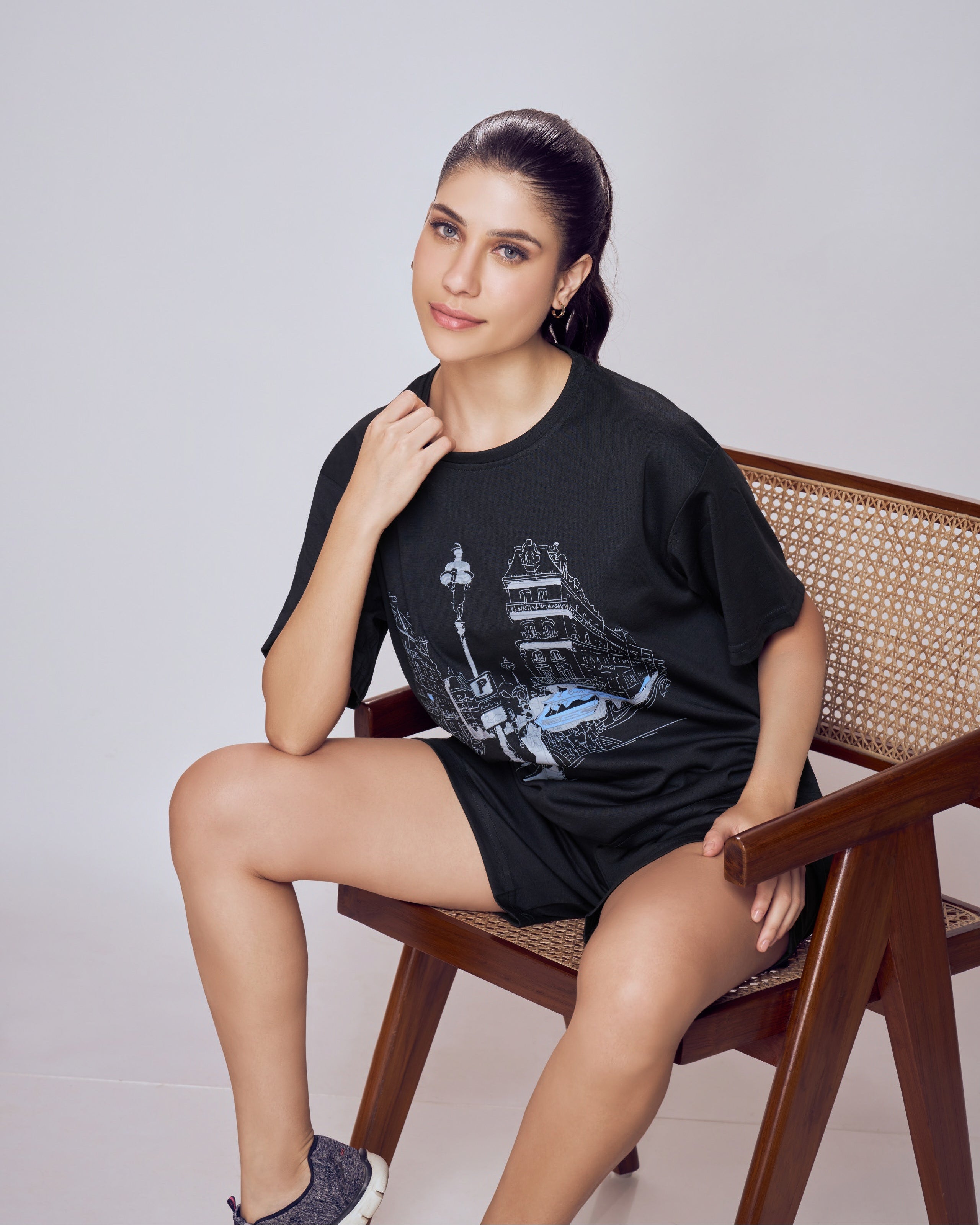 Woman sitting on a chair wearing a black t-shirt with a graphic design. Co-ord Set for Women