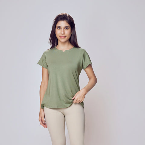 Woman wearing a green Cosy Cotton T-Shirt and beige leggings on a white background