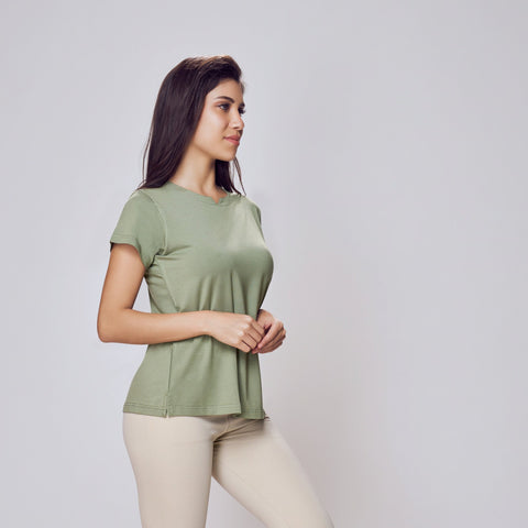 Woman wearing a green Cosy Cotton T-Shirt and beige leggings on a white background