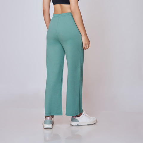 Woman wearing a black sports bra and teal leggings on a plain background