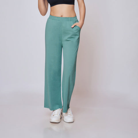 Woman wearing a black sports bra and teal pants on a gray background