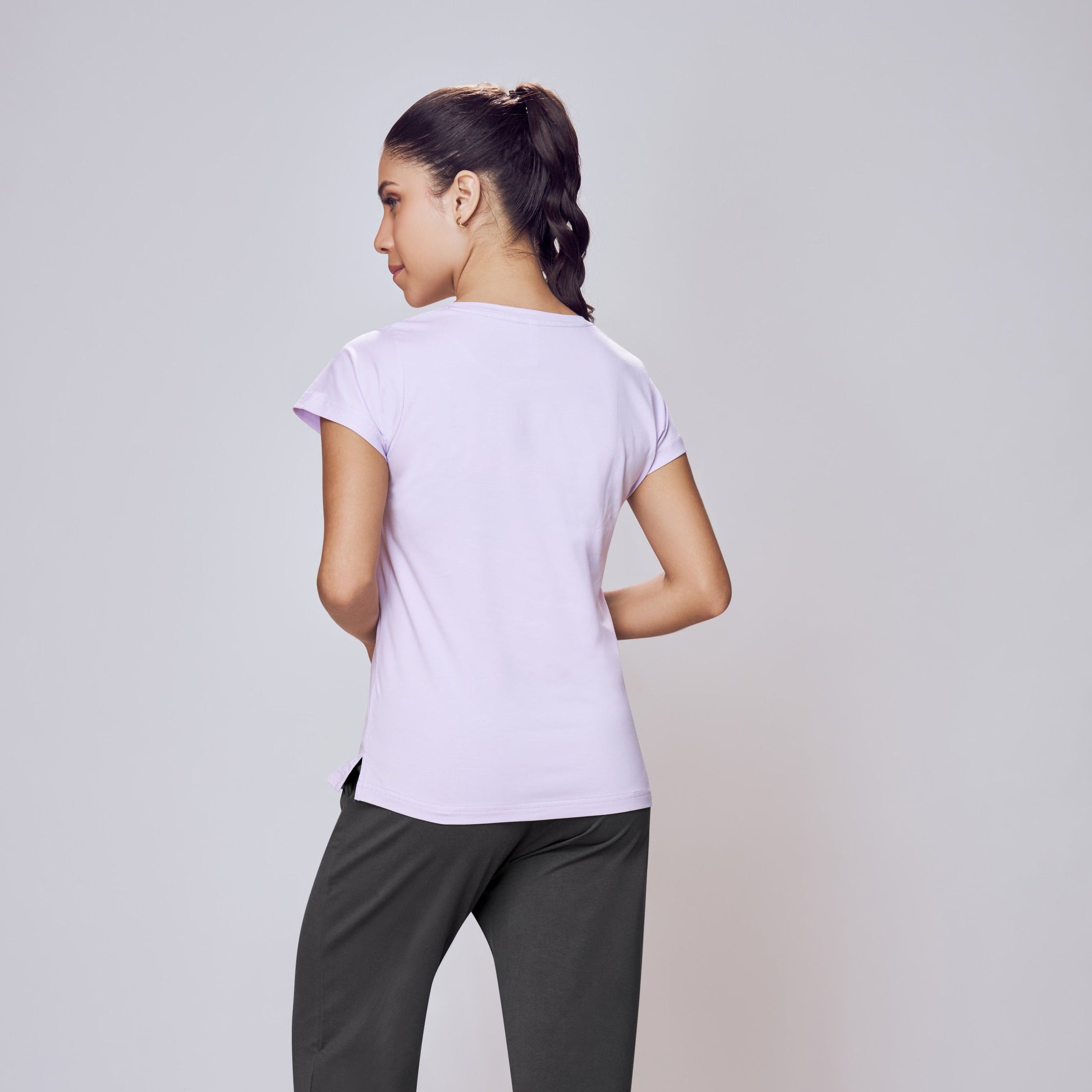 Person wearing a white t-shirt and dark pants on a light gray background