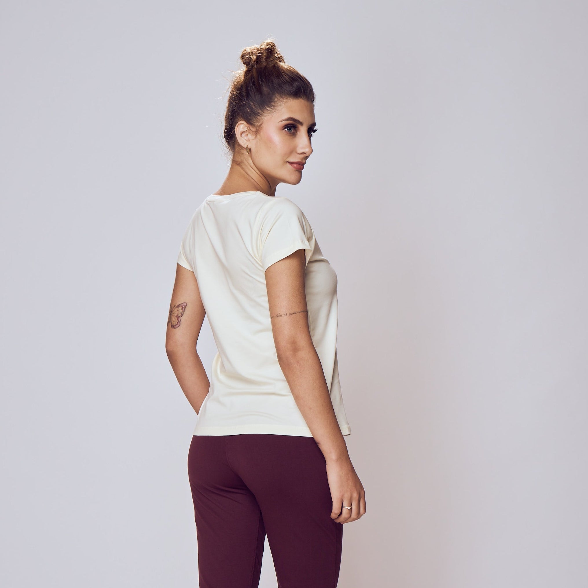 Woman wearing a white top and maroon pants on a plain background