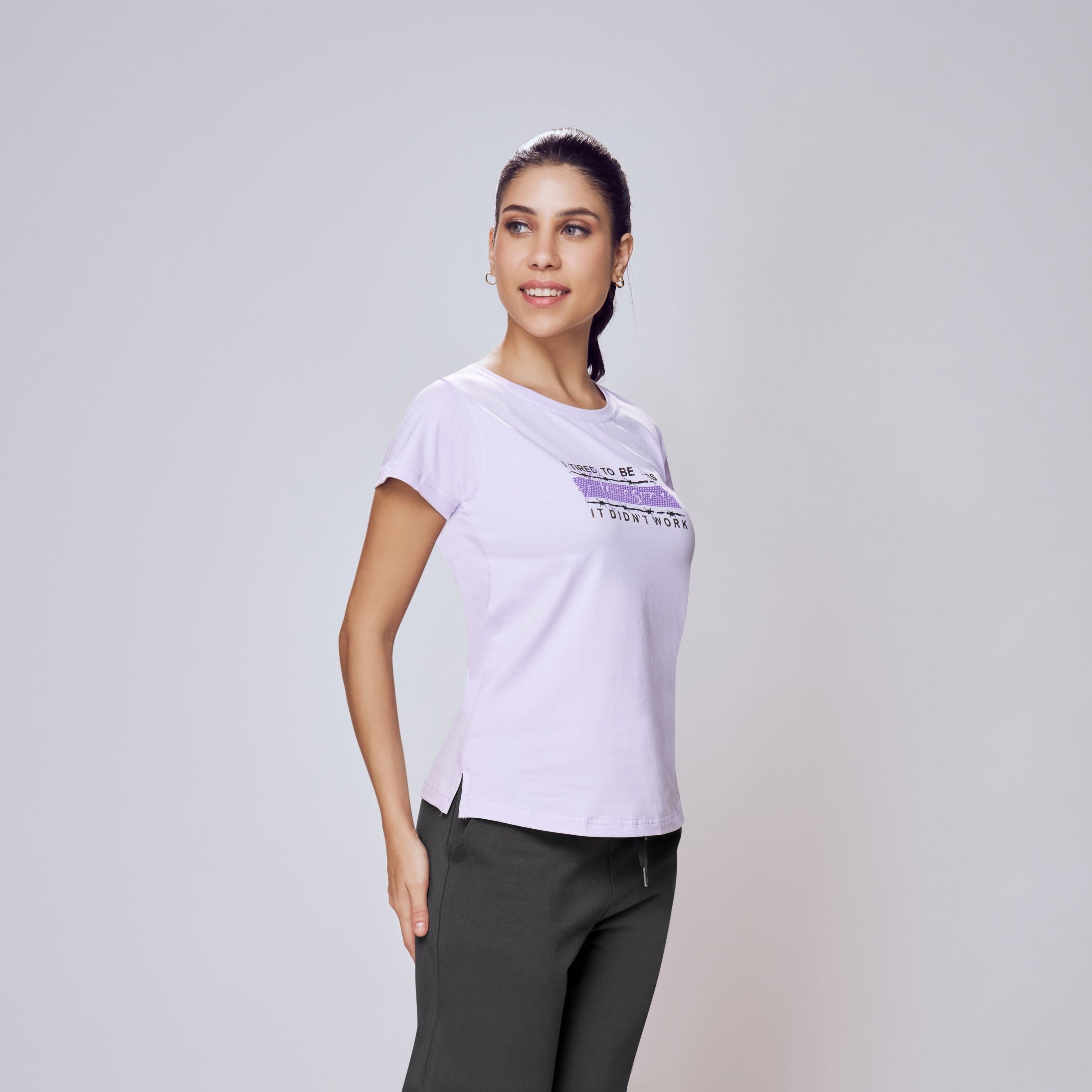 Woman wearing a white t-shirt with a logo and dark pants on a white background