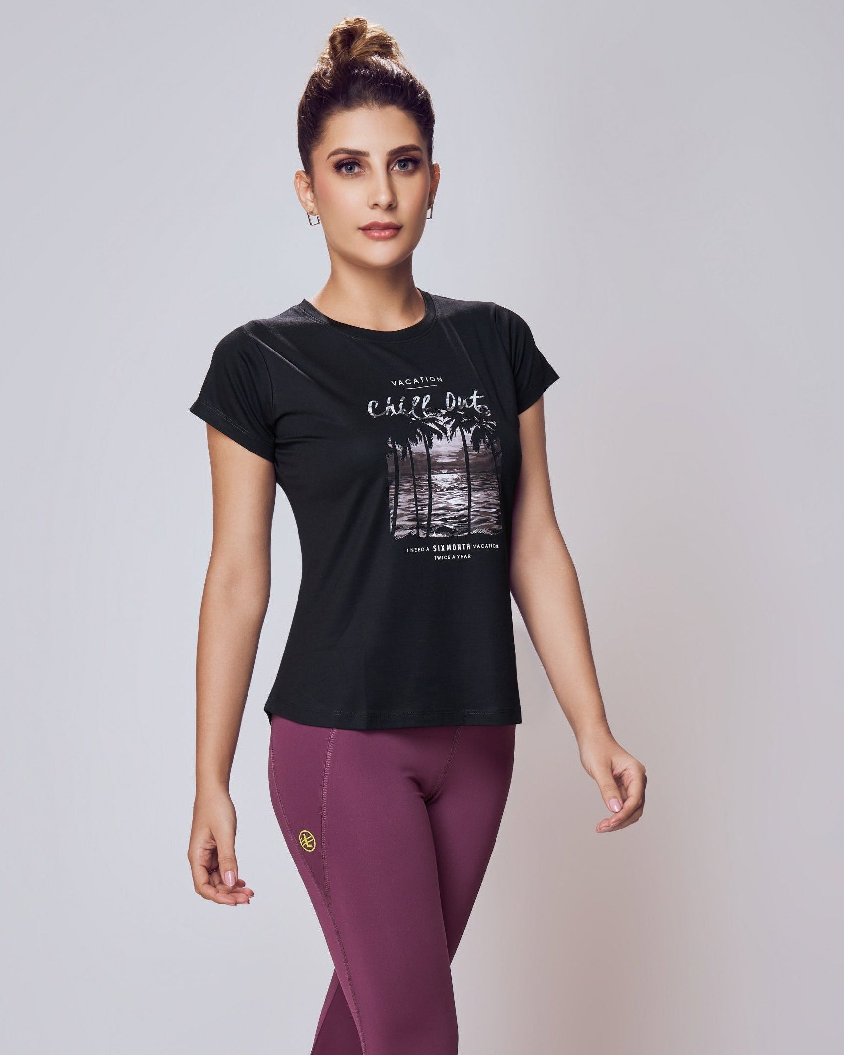 Woman wearing a black t-shirt and purple leggings on a white background