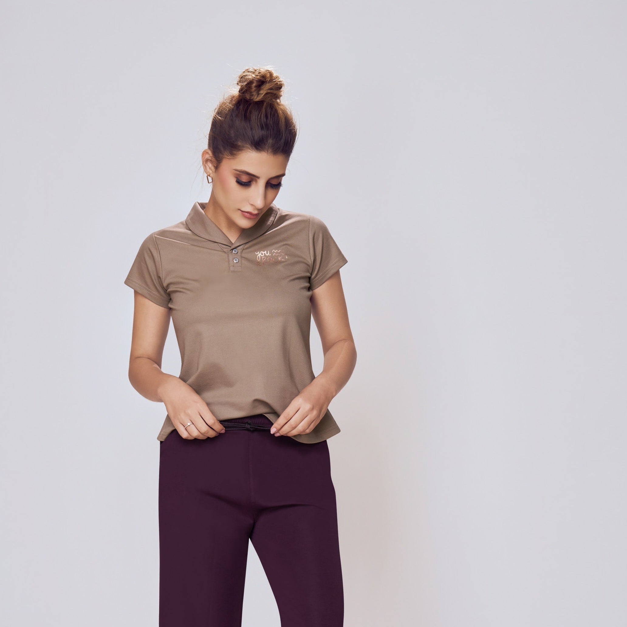 Woman wearing a brown top and purple pants on a white background