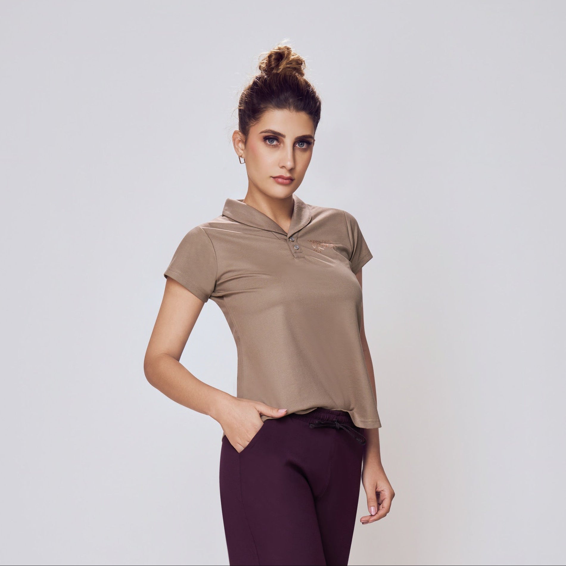 Woman wearing a beige top and purple pants on a white background