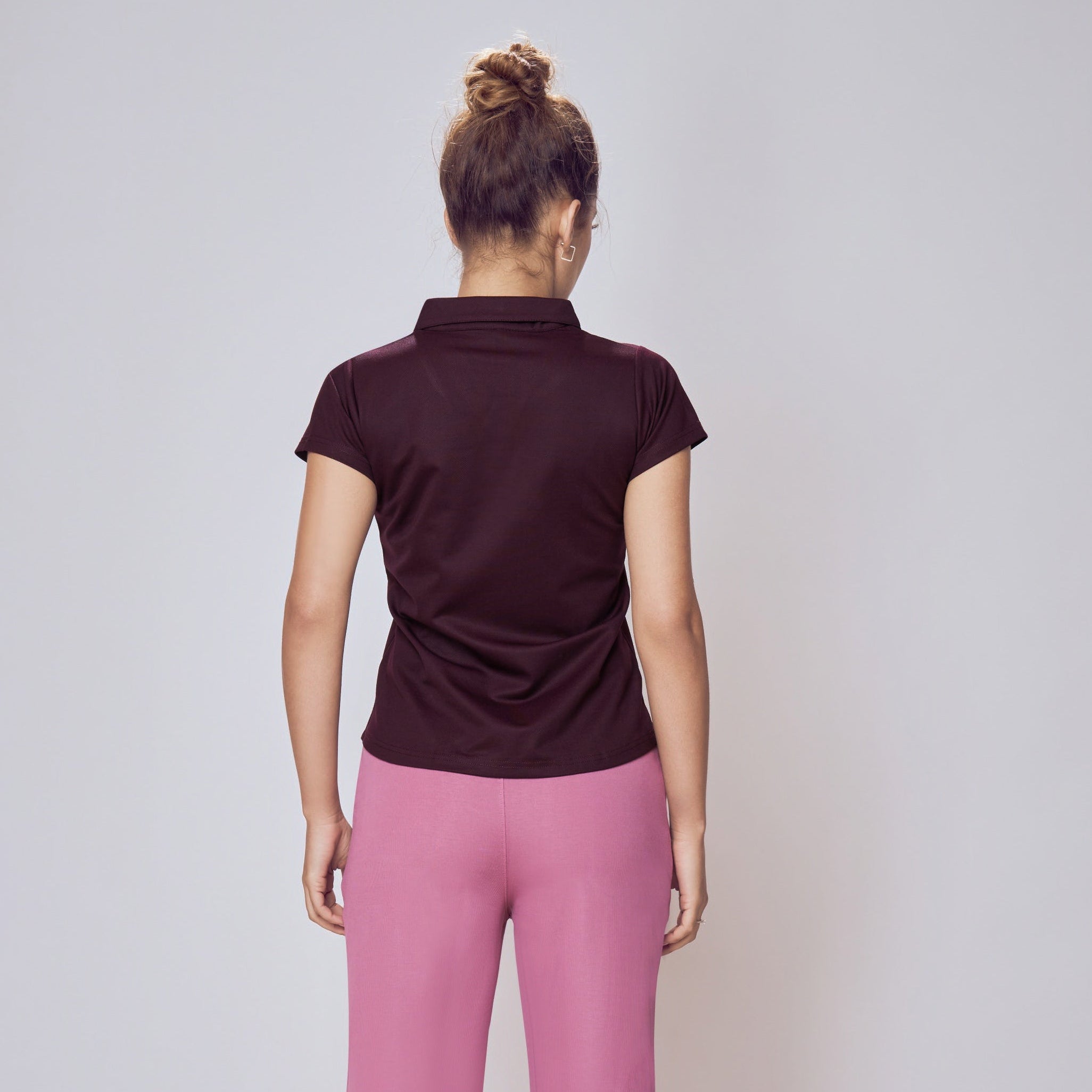 Person wearing a dark polo shirt and pink pants on a plain background