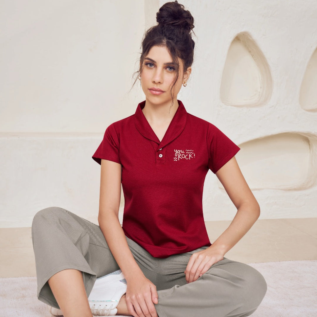 Woman wearing a red polo shirt sitting on a white surface with a neutral background