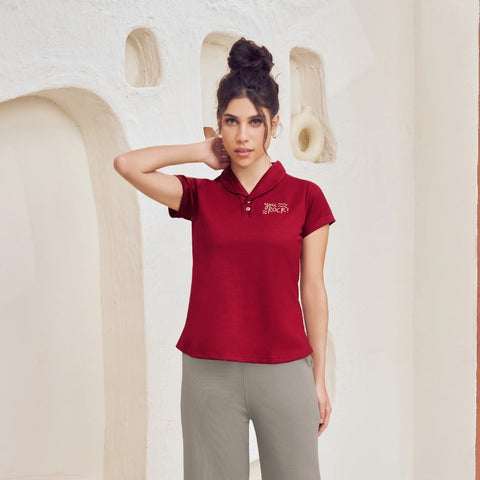 Woman wearing a red polo shirt and gray pants in a modern interior setting