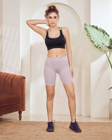 Woman in athletic Cycling Shorts for Women standing in a room with a plant and brown couch.