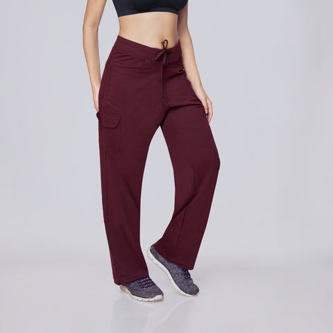 Woman wearing a black sports bra and maroon Essential Cargo Pants pants on a white background