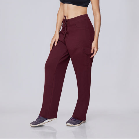 Woman wearing a black sports bra and maroon Essential Cargo Pants pants on a white background