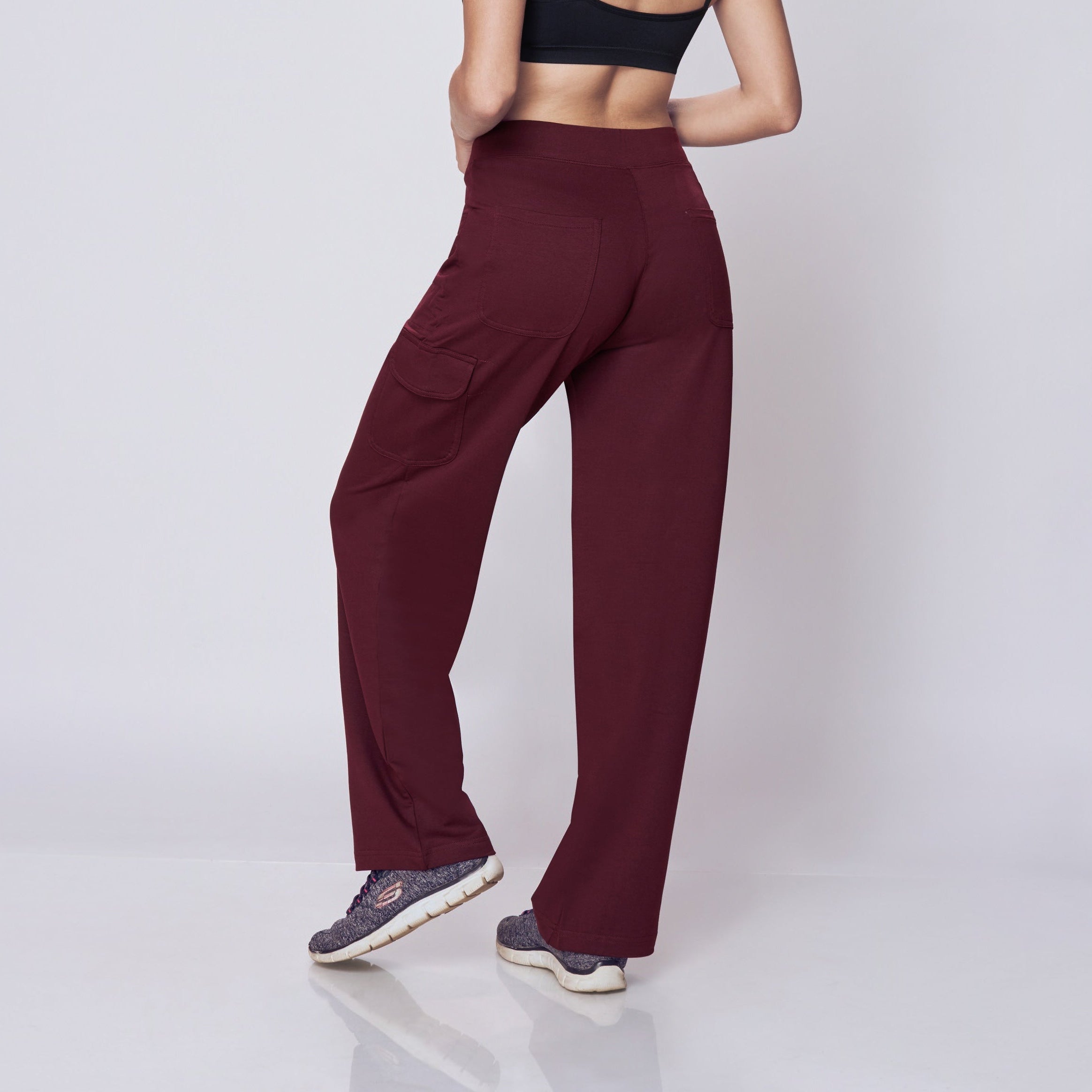 Woman wearing a black sports bra and maroon Essential Cargo Pants on a white background