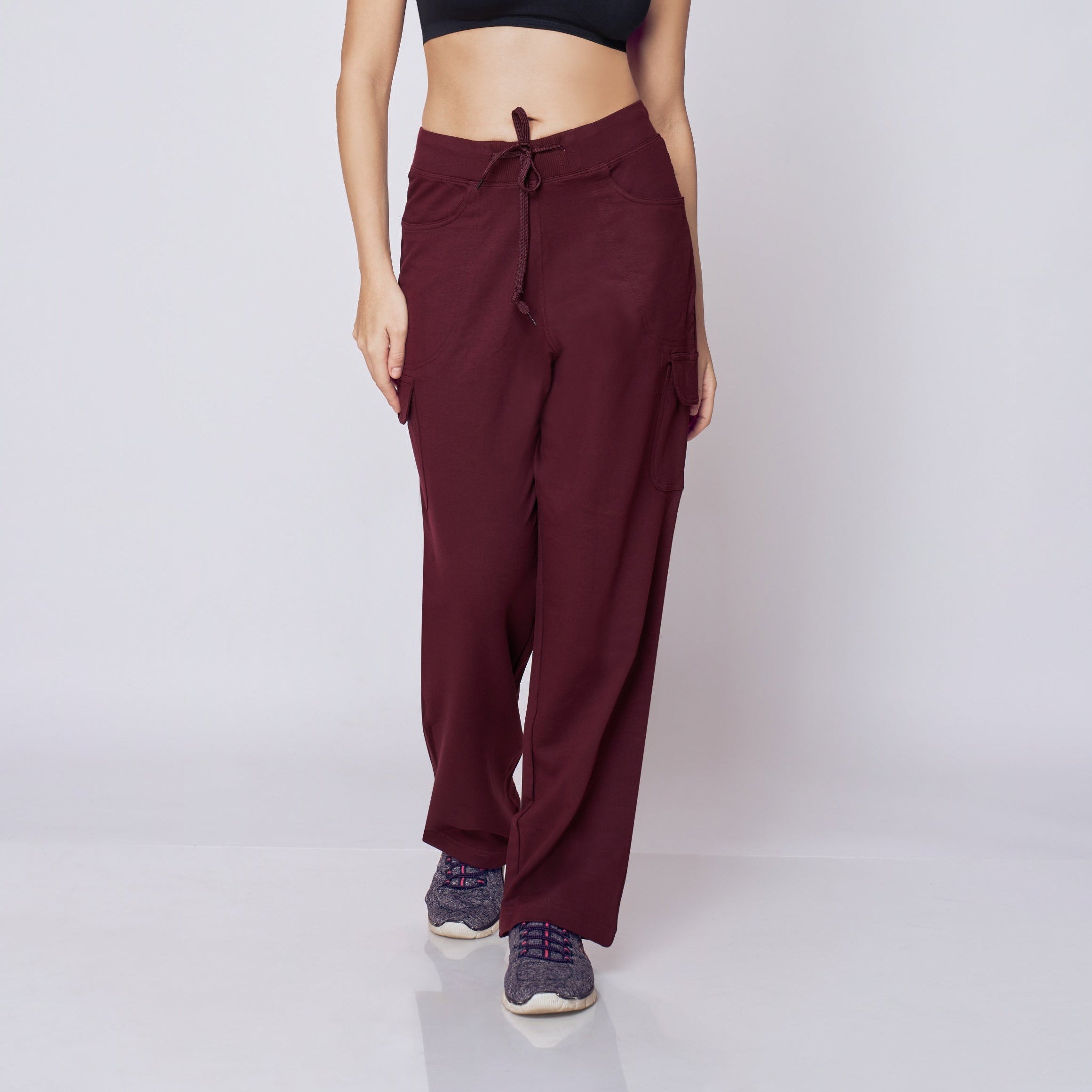 Woman wearing a black sports bra and maroon Essential Cargo Pants on a white background