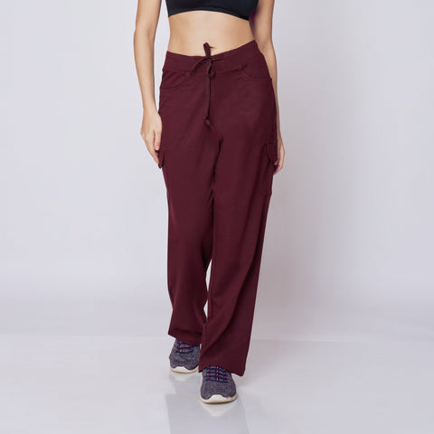 Woman wearing a black sports bra and maroon Essential Cargo Pants on a white background