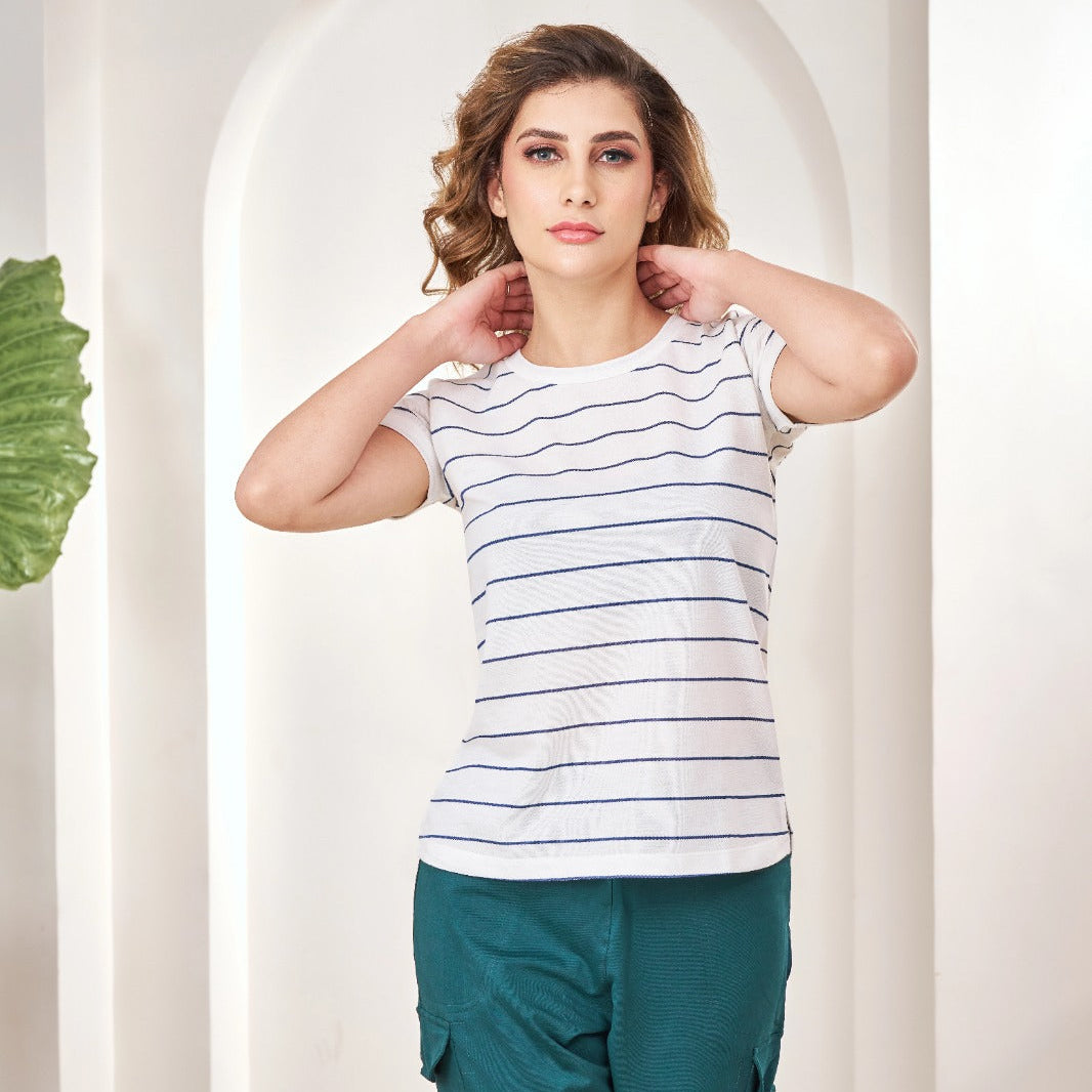 Woman sitting on a suitcase in a stylish interior setting wearing Feather Lite Stripped Tshirt 