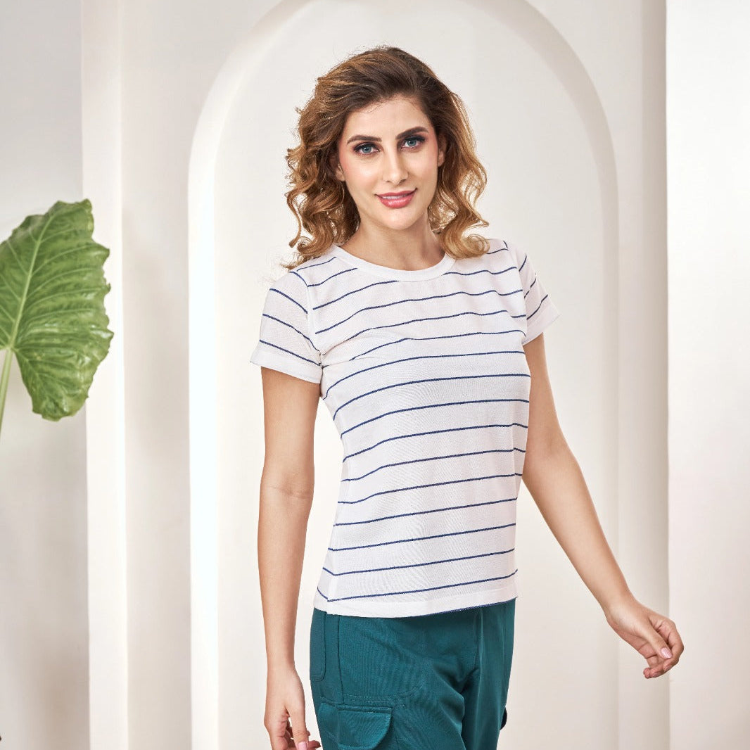 Woman sitting on a suitcase in a stylish interior setting wearing Feather Lite Stripped Tshirt 