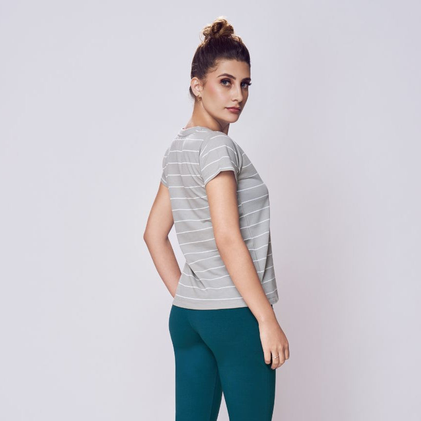 Woman wearing a striped shirt and teal pants on a white background