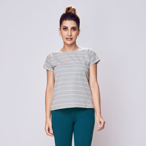 Woman wearing a striped t-shirt and teal leggings on a white background