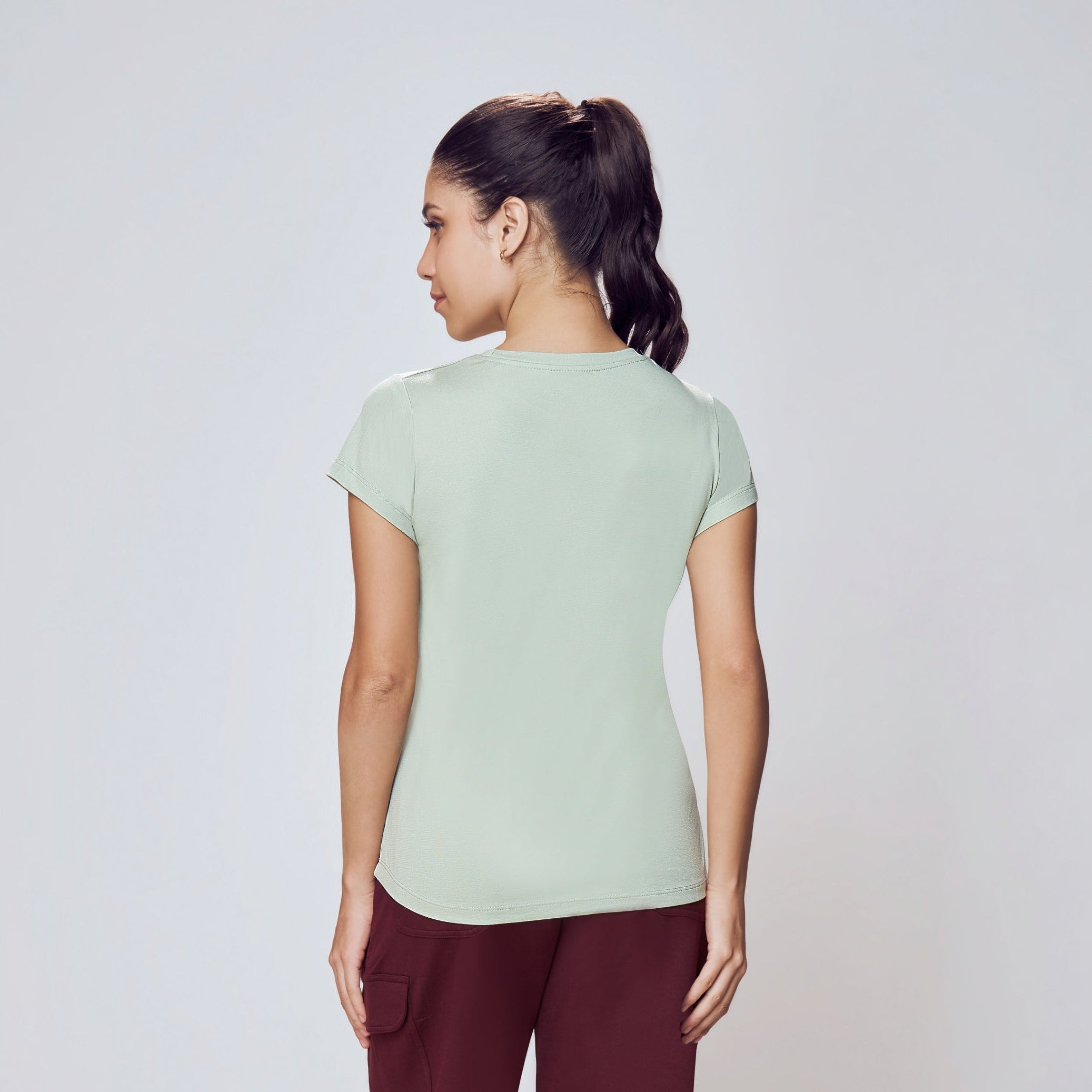 Person wearing a light green t-shirt and maroon pants on a white background