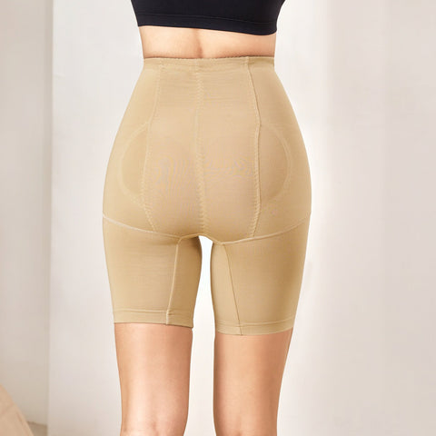 Woman wearing a black bra and beige shapewear against a plain background