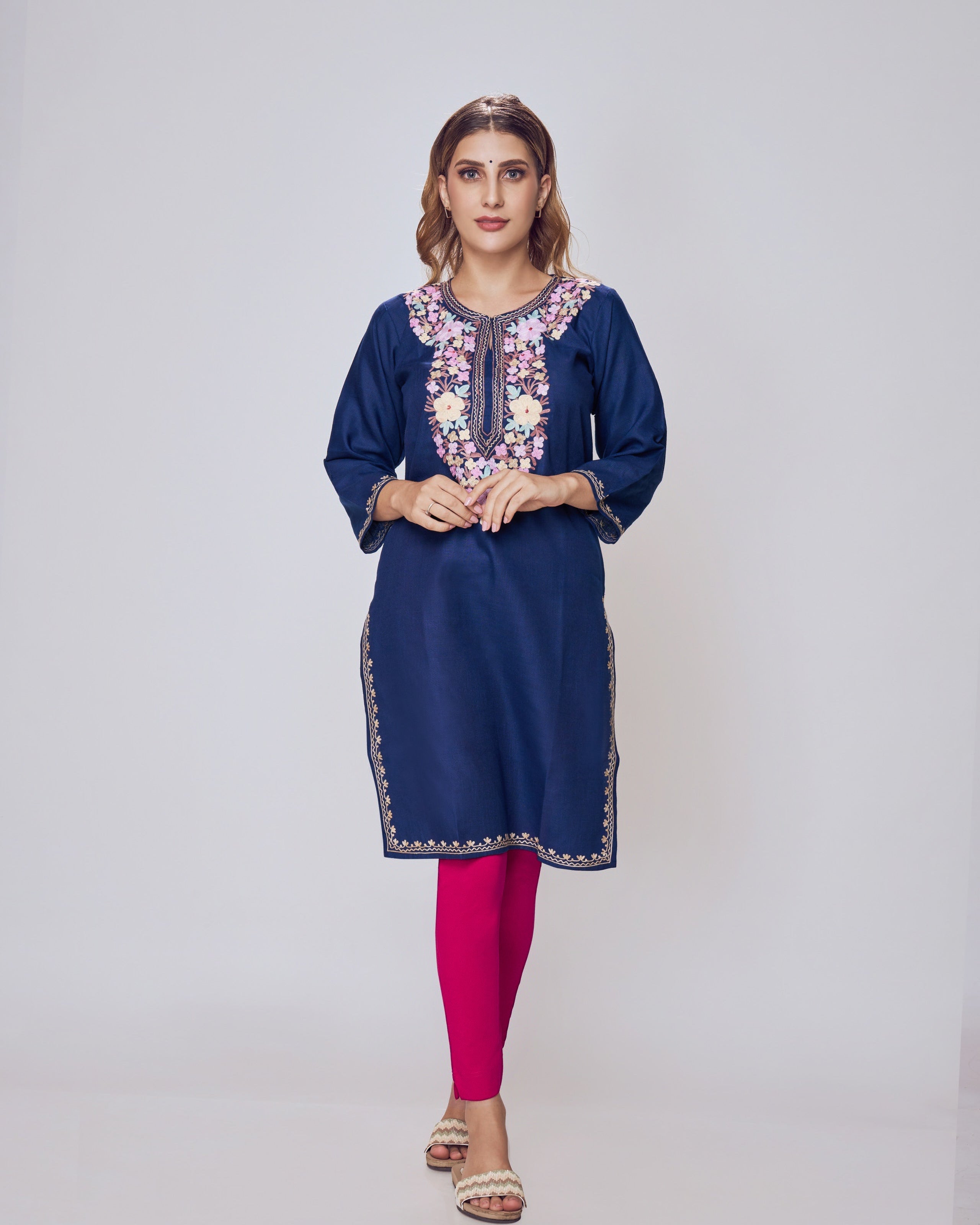 Woman wearing a blue embroidered kurta with pink leggings on a white background