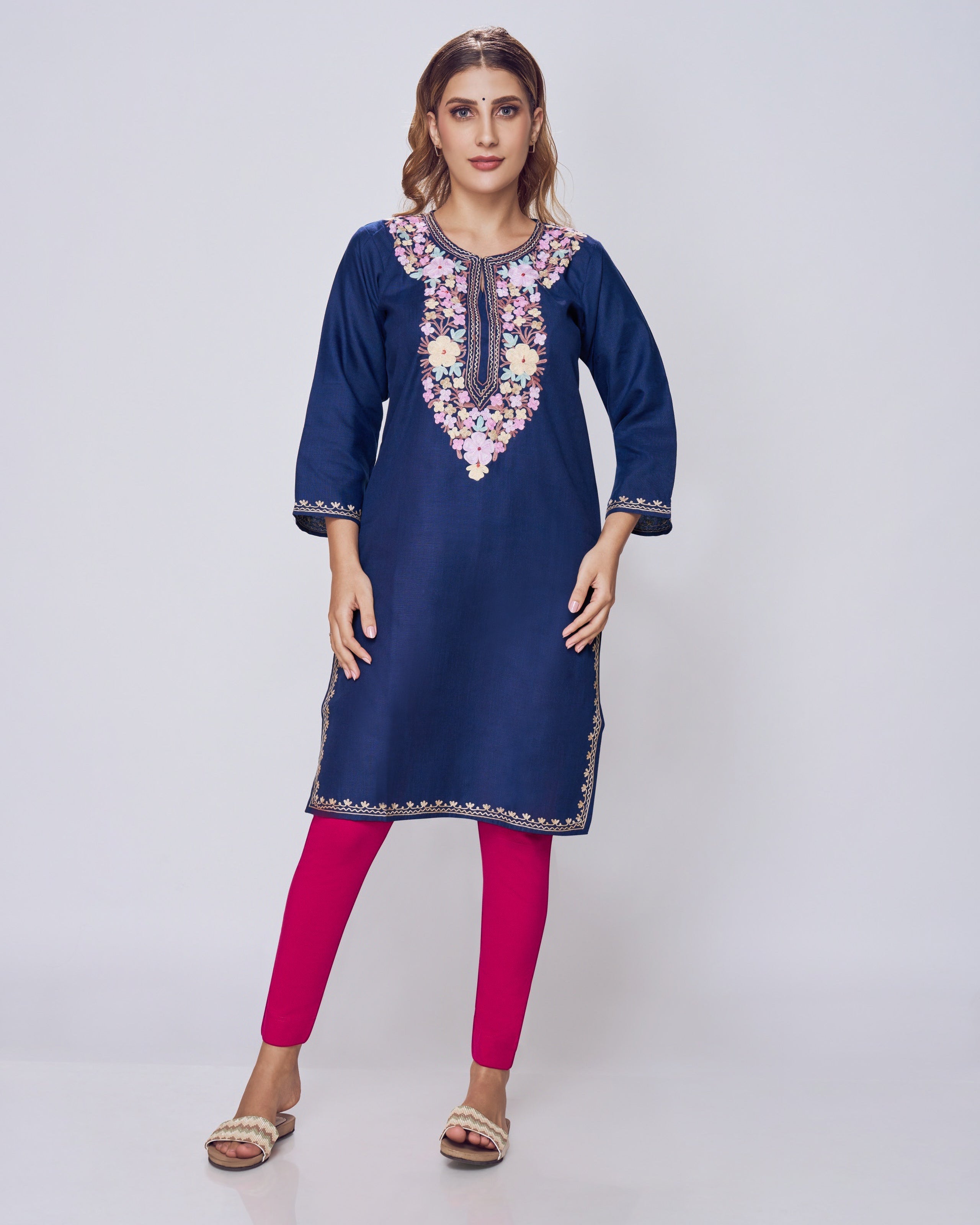 Woman wearing a blue embroidered kurta with pink leggings on a white background