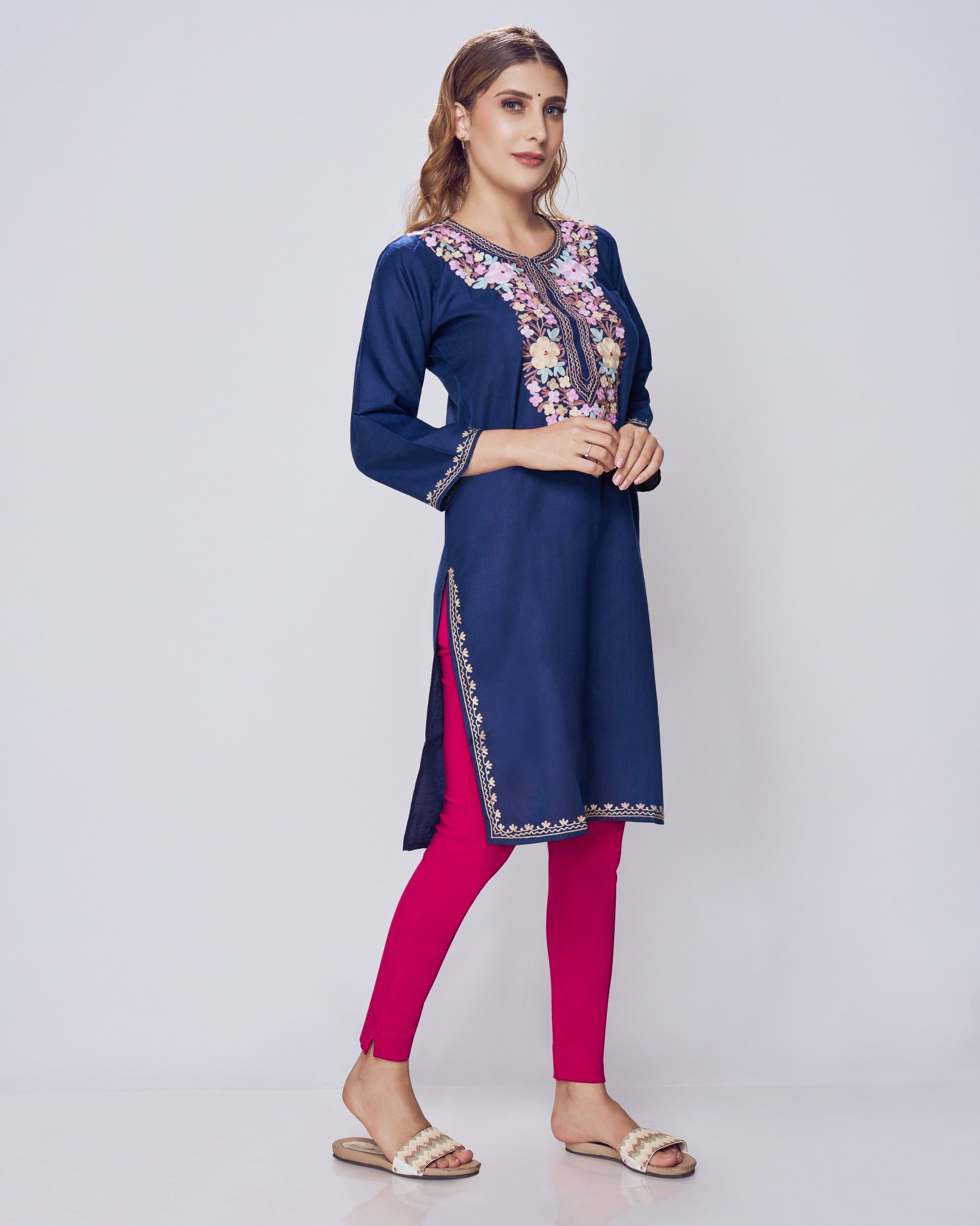 Woman wearing a blue embroidered kurta with pink leggings on a white background
