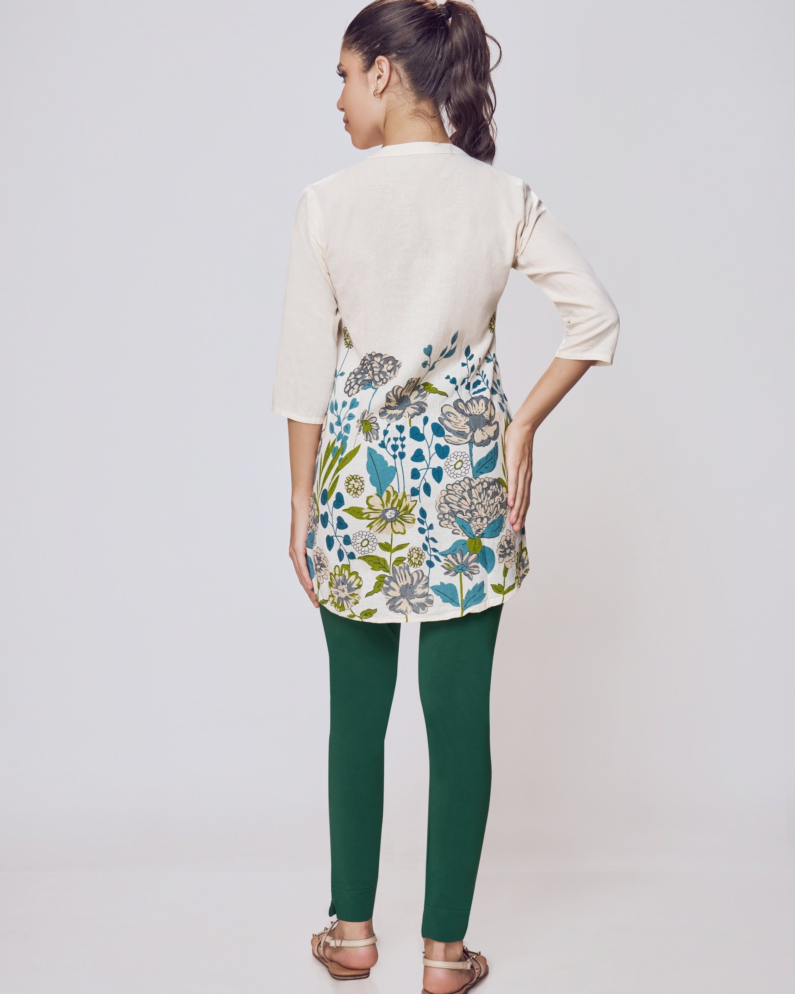 Woman wearing a floral dress over a beige cardigan on a white background